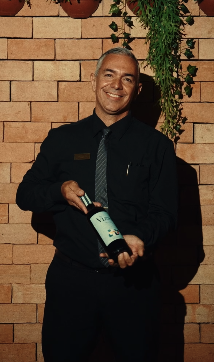Integrante da equipe da Villa Nostra com uma garrafa de vinho
